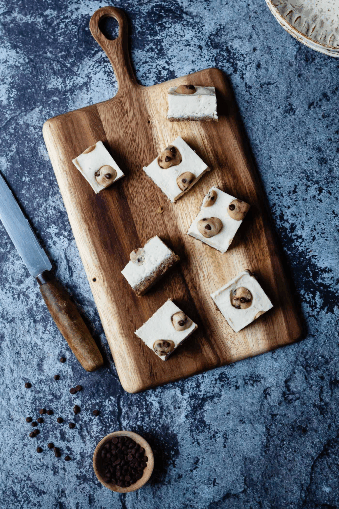 Vegan Cookie Dough Cheesecake Bars on a cutting board with knife