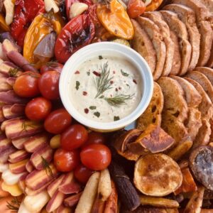 Tahini dip surrounded by roasted vegetables and crostini